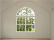 This oversized master bedroom shows cathedral ceilings and a decorative circle top window 